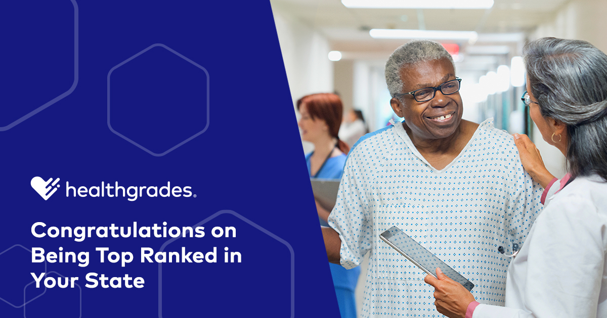 A senior Black patient in a hospital gown smiles as a female doctor with Brown skin and long grey hair speaks to him in a hospital hallway. White text to the left of the image says: Congratulations on Being Top Ranked in Your State.