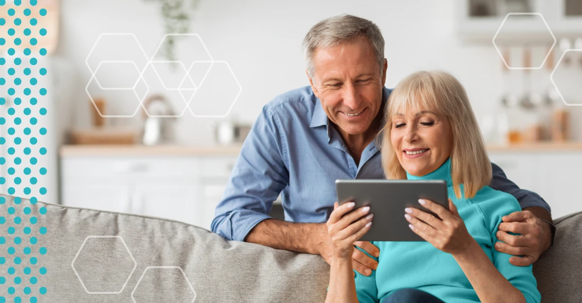 Man and women in their 50s or 60s look at a tablet together in their home