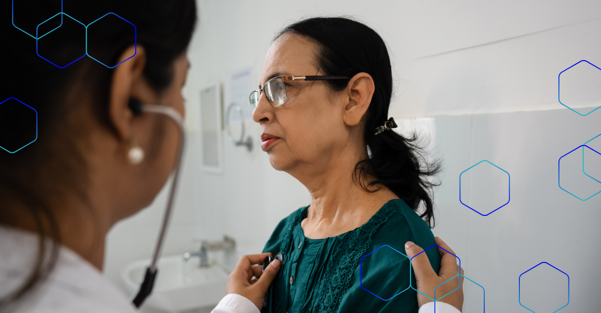 A stock photo of a doctor using a stethoscope to listen to the heartbeat of a senior female patient. The setting is an exam room and the image features a blue-and-teal hexagonal pattern.